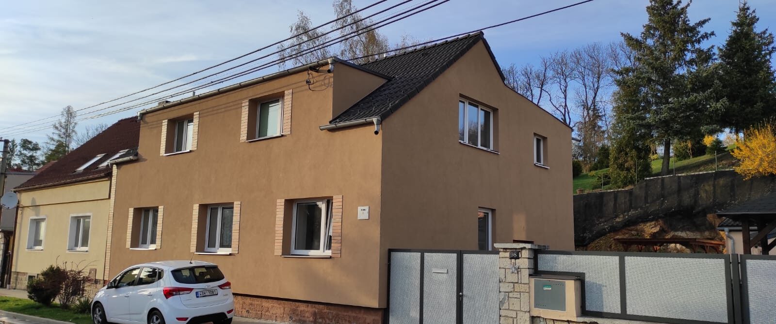 Zateplený rodinný dům s okrovou fasádou a dekorativními šambránami kolem oken